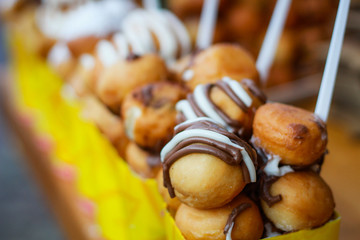 Mini donuts with chocolate. Street food in Bulgaria. Cookies in yellow boxes with a fork.
