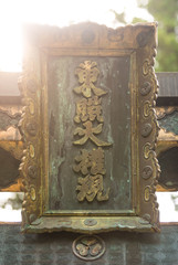 Close up of an ancient bronze japanese inscription flooded in light in a shinto temple