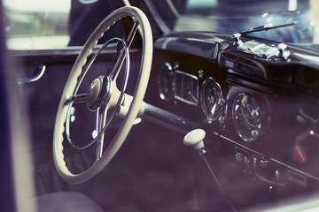 Close-up of the cockpit of a classic car showing steering wheel and gear