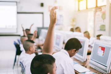 Student hands up answer a question in class computer at the elementary school. Education concept.