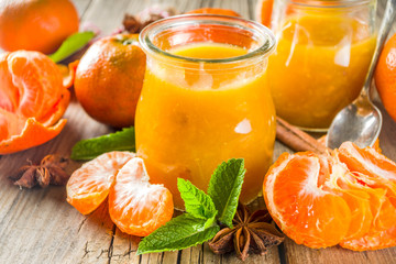 Autumn season conservation concept. Homemade tangerine jam, with spices and mint. On a rustic wooden table, copy space