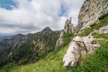 Wide angle landscape of Italian Alps, with a boulder in the foreground and rocky peaks in the...