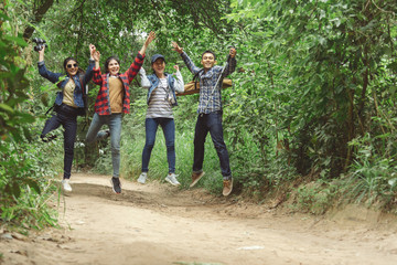 Fototapeta premium Happy smiling friends with musical instruments jumping in the forest outdoors