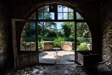 In an abandoned building, an art nouveau french window leads to a terrace surrounded by trees and vegetation