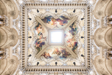 Symmetrical shot of the vault of a french building decorated with a fresco and a central skylight