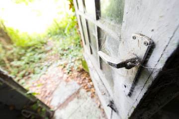 Close up of the door of an old and abandoned building, with the handle covered with spiderwebs