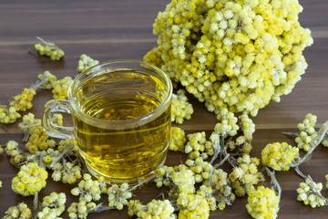 The Helichrysum Arenarium golden grass on the wooden background.