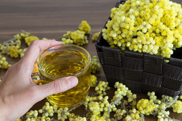 The Helichrysum Arenarium golden grass on the wooden background.