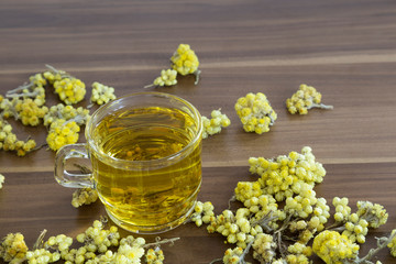 The Helichrysum Arenarium golden grass on the wooden background.