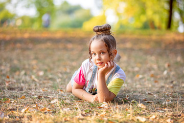 portrait of a little girl lying on a colorful leaves in autumn park