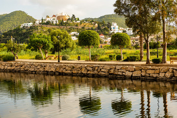 Fototapeta na wymiar River Walk in Santa Eulalia with town Church view and Tree reflection