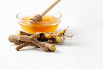 Raw root plant Rumex crispus (yellow dock) and honey on white concrete background
