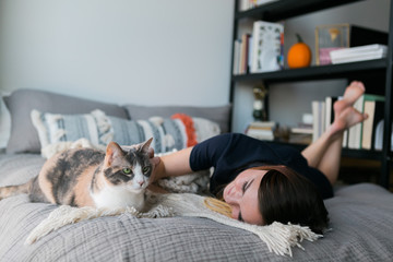 Cute girl cuddling with calico cat on bed in apartment, copy space, sweet