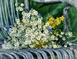 Obraz na płótnie Canvas Bouquet of wildflowers on old wicker garden furniture. A simple bouquet of daisies.