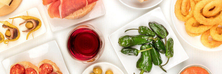 Spanish tapas and wine, an overhead panoramic shot of a variety of snacks. Padron peppers, jamon,...