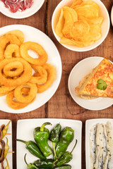 Spanish tapas, a variety of snacks. Squid rings, tortilla, sardines, padron peppers, top shot on a dark rustic wooden background,