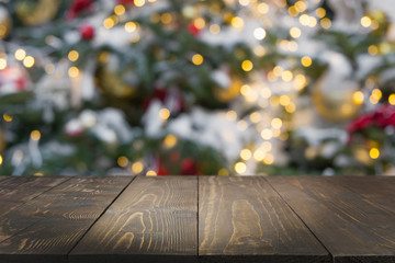 Wooden dark tabletop and blurred christmas tree bokeh. Xmas background for display your products.