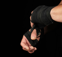 Fototapeta premium man wraps his hands in black textile bandage for sports