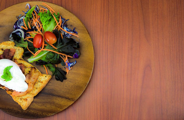 Homemade meal, Organic egg benedict with fresh salad on wood plate for healthy breakfast in wood background
