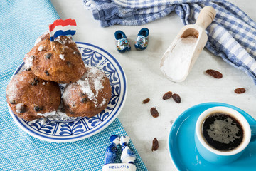 Oil dumplings (oliebollen) on blue plate, with wooden shoes, sugar spoon and coffee. Traditional treat on New Years Eve in The Netherlands