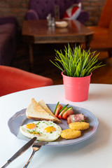 Traditional british breakfast with fried egg, wheat crunchy toasts, potato hash browns, bacon and salad