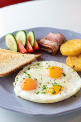 Close up of british breakfast with fried egg, wheat crunchy toasts, potato hash browns, bacon and salad