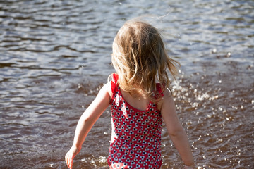 little girl standing before lake water surface