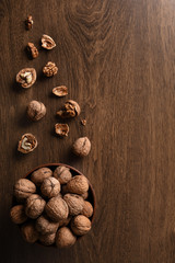  Walnuts nuts in a bowl on a dark brown wooden background in a dark key