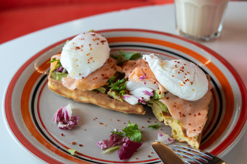 Close up of healthy ketogenic breakfast: soft waffle, mashed avocado, salmon, poached egg and coffee