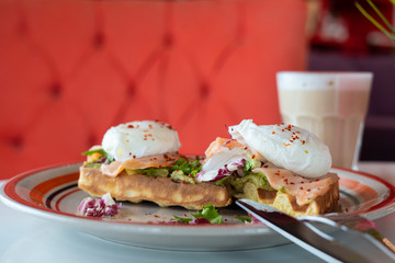 Fancy breakfast with soft waffle, mashed avocado, salmon, poached egg and coffee