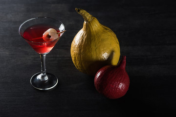 ripe pumpkins and red cocktail on black background