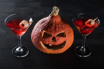 spooky Halloween pumpkin and red cocktails on black background