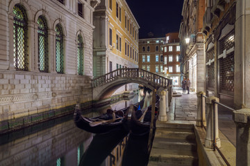 Narrow canal between colorful historic houses in Venice at night.