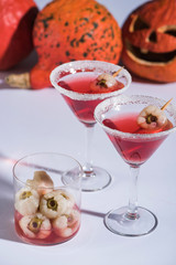 red Halloween cocktails with decoration in glasses on white surface