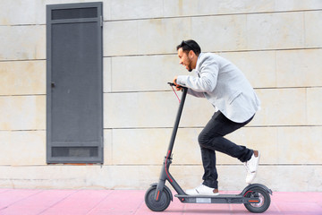 Latin adult man with sunglasses, well dressed and drive electric scooter on the street