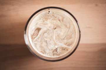 Top view of a glass of coffee on a wooden board background