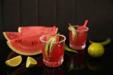 Alcoholic drink for a Mexican party celebrating Cinco de Mayo. Margarita cocktail, ice cream, tequila and lime, hot chili peppers and watermelon, dark background with reflection. With copy space 