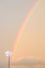 rainbow in an orange cloudy sky above a baseball stadium