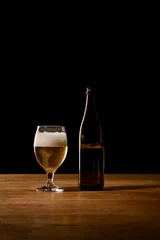 Fotobehang beer in bottle and glass on wooden table isolated on black © LIGHTFIELD STUDIOS