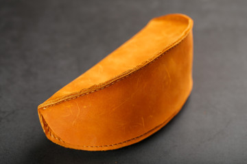 Brown case wallet for glasses made of genuine nubuck leather on a dark background with sunglasses