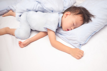 Cute little Asian 3 - 4 years old toddler boy kid in pajama sleeping / taking a nap on a blue pillow in bed , Bedtime for kids concept with copy space