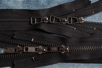 Pack a lot of black metal antique zippers stripes with sliders pattern for handmade sewing tailoring haberdashery leather craft on the blue denim background