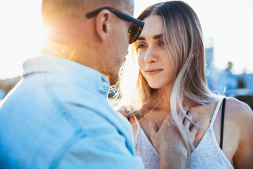 Naklejka premium Tanned young caucasian couple, modern lovestory in film grain effect, vintage style. Sunset time. Close up of emotions and feelings, tender and happy, summer. Honeymoon concept. Toned in teal orange.