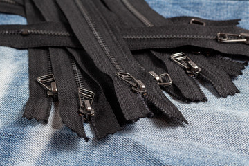 Pack a lot of black metal antique zippers stripes with sliders pattern for handmade sewing tailoring haberdashery leather craft on the blue denim background