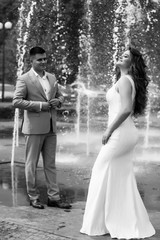 Beautiful smiling love couple near fountain outdoors in the city. Handsome young man and woman. Romantic young couple in love. Pretty girl and boy. Black and white