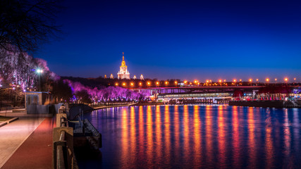 A beautiful shot of a river with the reflection of city lights and an illuminated bridge and historical building in the background
