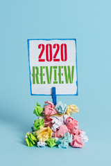 Word writing text 2020 Review. Business photo showcasing seeing important events or actions that made previous year Reminder pile colored crumpled paper clothespin reminder blue background