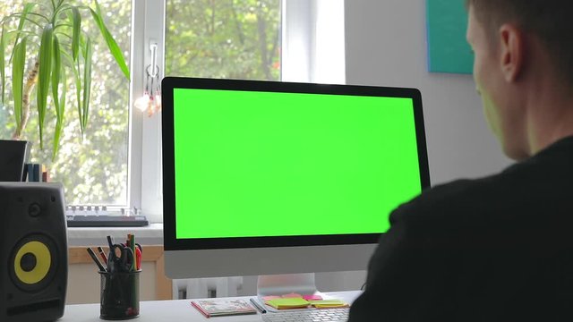 Smart man working at home in loft room on personal computer with green screen and chroma key writing programming code for new business 5g platform freelance