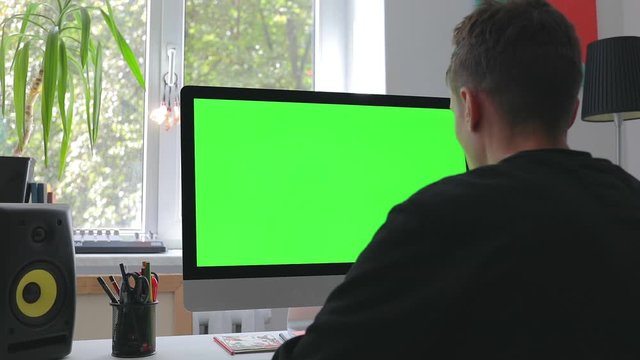 Smart man working at home in loft room on personal computer with green screen and chroma key writing programming code for new business 5g platform freelance