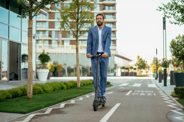 Young businessman in a suit riding an electric scooter © JustLife